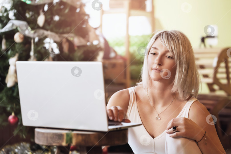 Скачать Спортивная блондинка проводит онлайн-урок для своих клиентов, сидя в спортивной одежде в студии перед ноутбуком фотосток Ozero