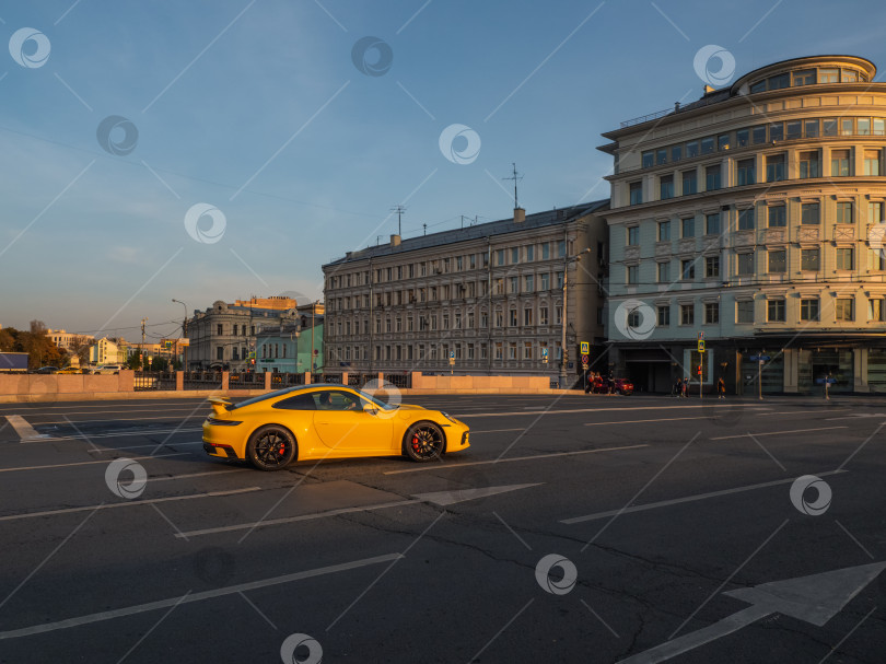 Скачать Желтый Porsche 911 в пробке на улице в Москве вечером. фотосток Ozero