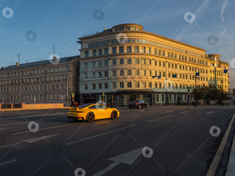 Скачать Желтый Porsche 911 в пробке на улице в Москве вечером. фотосток Ozero