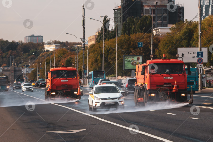 Скачать Поливальные машины работают на городской улице. фотосток Ozero