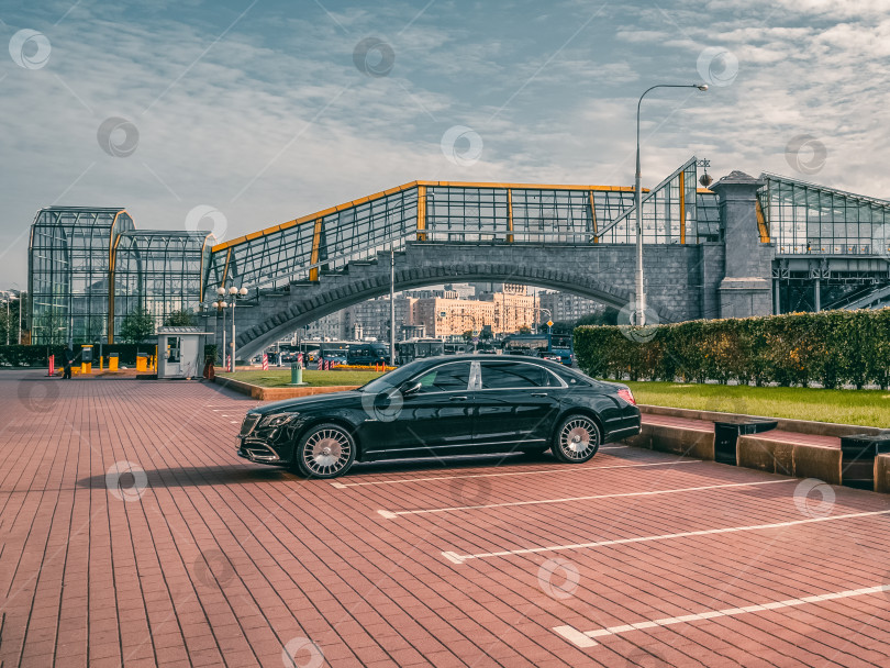 Скачать Черный современный лимузин Mercedes-Maybach стоит на парковке под осенним солнцем на улице. фотосток Ozero