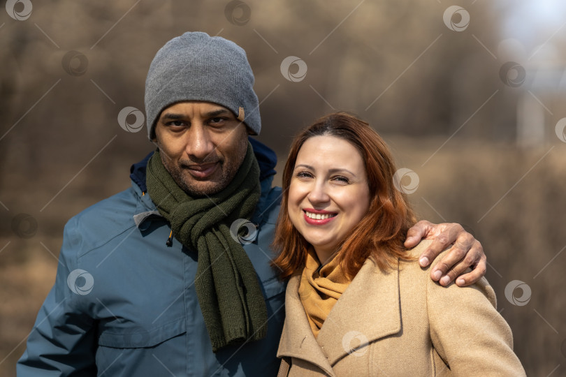 Скачать Межрасовая пара позирует на прогулке в парке, желтокожий араб-мужчина и белокожая рыжеволосая женщина. Семья фотосток Ozero