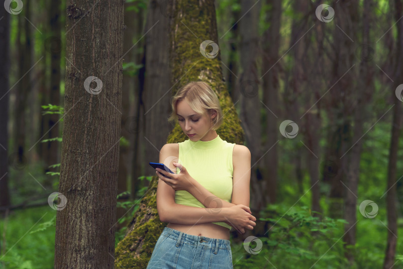 Скачать молодая женщина со смартфоном в природном лесопарке фотосток Ozero