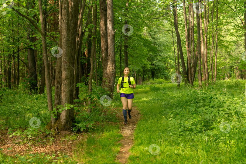 Скачать молодая женщина совершает пробежку трусцой по дорожке в природном лесопарке фотосток Ozero