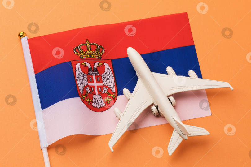 Скачать Сербский флаг и игрушечный самолет на цветном фоне, концепция на тему путешествия в Сербию фотосток Ozero