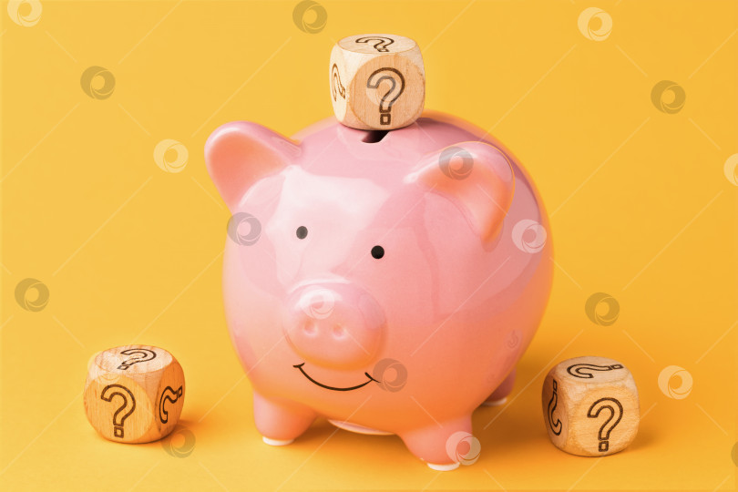 Скачать Деревянные кубики со знаком вопроса рядом с копилкой на цветном фоне, концепция выбора валюты для хранения денег фотосток Ozero