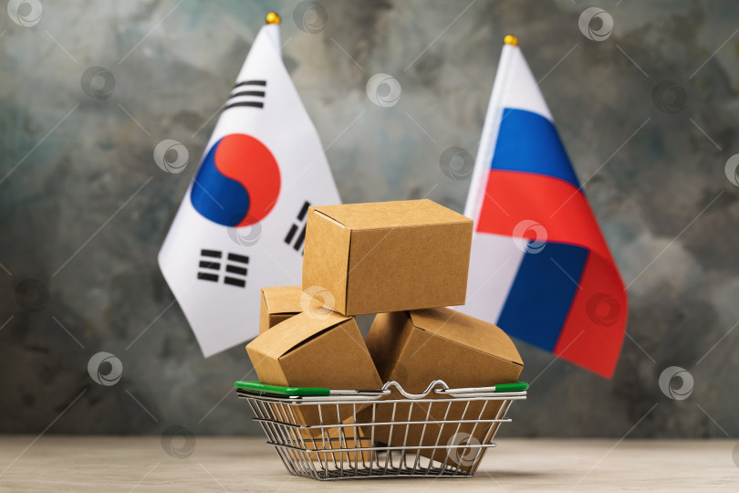 Скачать Корзина с продуктами, полная коробок, флаги России и Южной Кореи на абстрактном фоне, концепция торговли между Южной Кореей и Россией фотосток Ozero