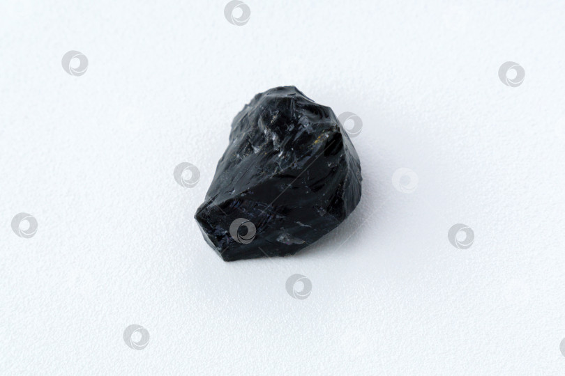 Скачать Черный обсидиановый камень на белом фоне. Натуральное стекло. Черный минеральный драгоценный камень фотосток Ozero