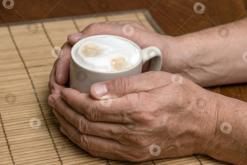 Скачать Чашка свежего кофе с пенкой капучино в руках мужчины крупным планом фотосток Ozero