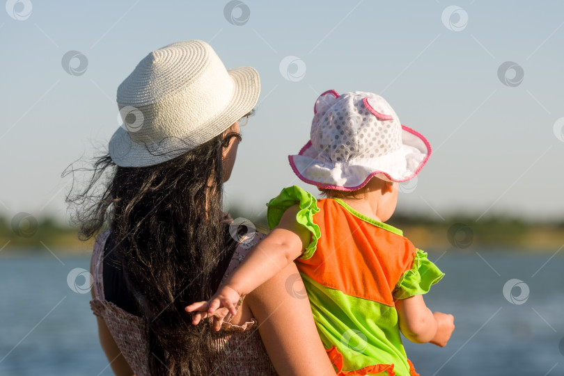 Скачать Молодая мать с маленькой дочерью на берегу озера - вид сзади фотосток Ozero