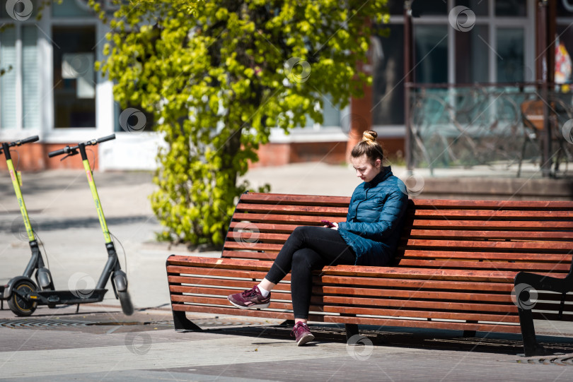 Скачать Россия, Санкт-Петербург, май 2022 года: Молодая женщина на скамейке в парке фотосток Ozero