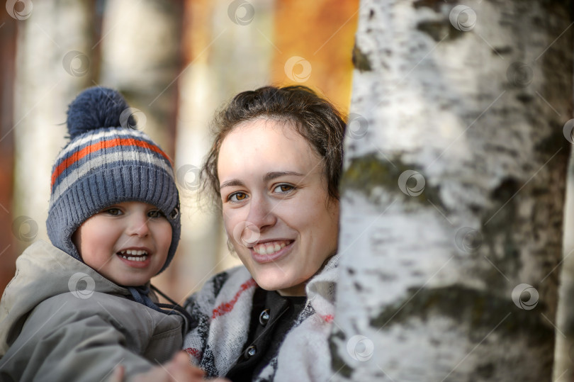 Скачать Счастливая молодая мать с маленьким сыном на руках в осеннем парке - крупный план фотосток Ozero