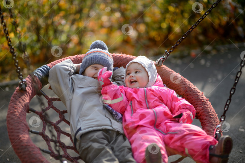 Скачать Маленькие дети, мальчик и девочка, катаются на качелях фотосток Ozero