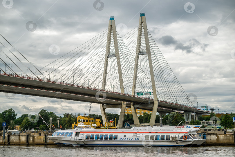 Скачать Россия, Санкт-Петербург, 4 августа 2022 года: Прогулочный катер у причала на Неве под вантовым мостом фотосток Ozero