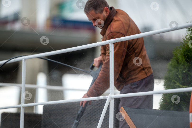 Скачать Россия, Санкт-Петербург, 10 сентября 2022 года: Мужчина моет палубу яхты шлангом фотосток Ozero
