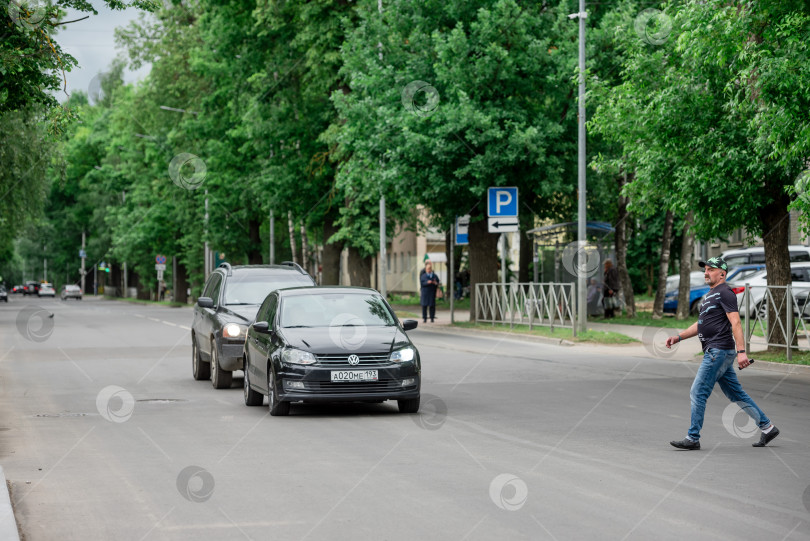 Скачать Россия, Гатчина, 20 мая 2022 года: человек переходит дорогу в городе не по пешеходному переходу фотосток Ozero