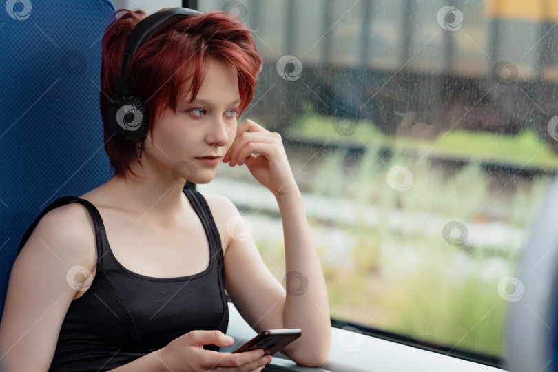 Скачать молодая женщина, едущая в поезде и слушающая музыку в наушниках фотосток Ozero
