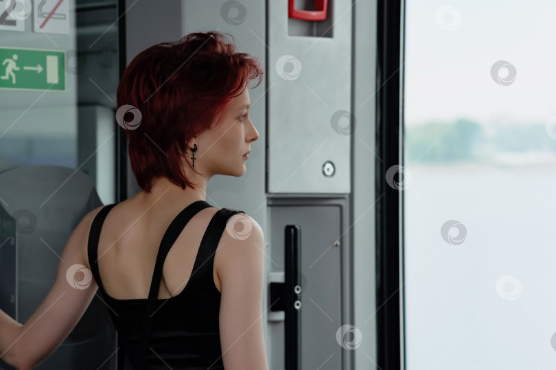 Скачать девушка стоит в вагоне движущегося пригородного поезда перед дверью, глядя на море фотосток Ozero