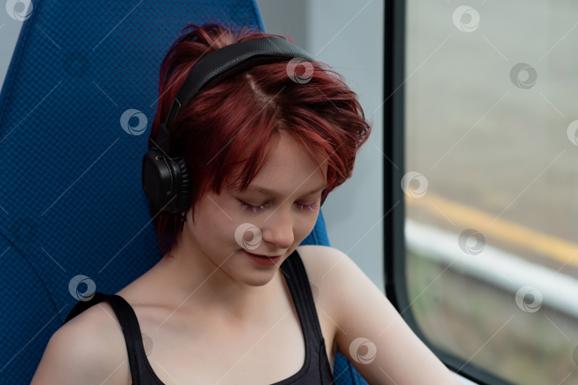 Скачать молодая женщина слушает музыку в наушниках во время поездки на скоростном поезде фотосток Ozero