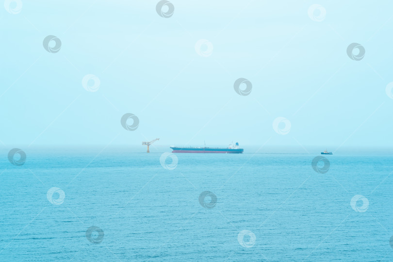 Скачать туманный морской пейзаж с танкером возле нефтяного терминала, расположенного далеко в море фотосток Ozero
