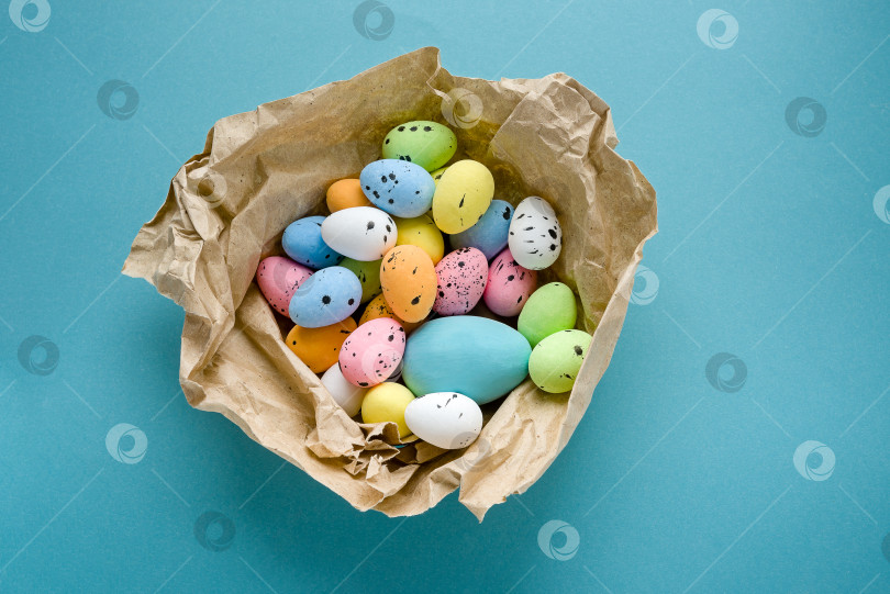 Скачать Яйца, раскрашенные в голубой, розовый, желтый, зеленый цвета на синем фоне из крафт-бумаги фотосток Ozero