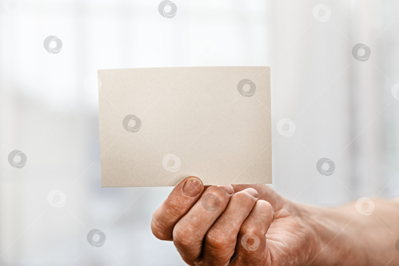 Скачать Белая пустая карточка в руке мужчины на белом фоне. Заготовка для дизайнерской надписи. фотосток Ozero