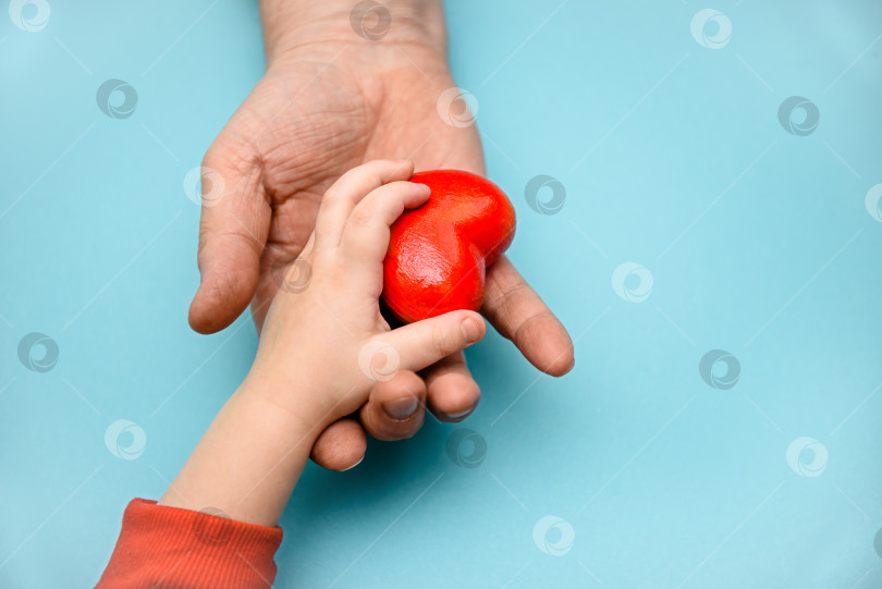 Скачать Взрослые и детские руки держат красное сердечко - концепцию здоровья, любви и семьи. День матери, День здоровья. фотосток Ozero