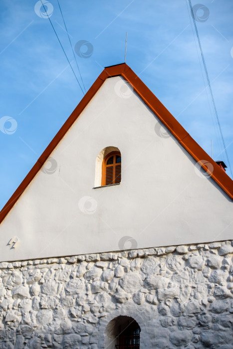 Скачать фасад старого здания с белой штукатуркой на фоне голубого неба фотосток Ozero