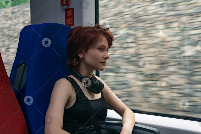 Скачать молодая женщина едет в движущемся пригородном поезде, за окном - габионная стена, размытая в движении фотосток Ozero