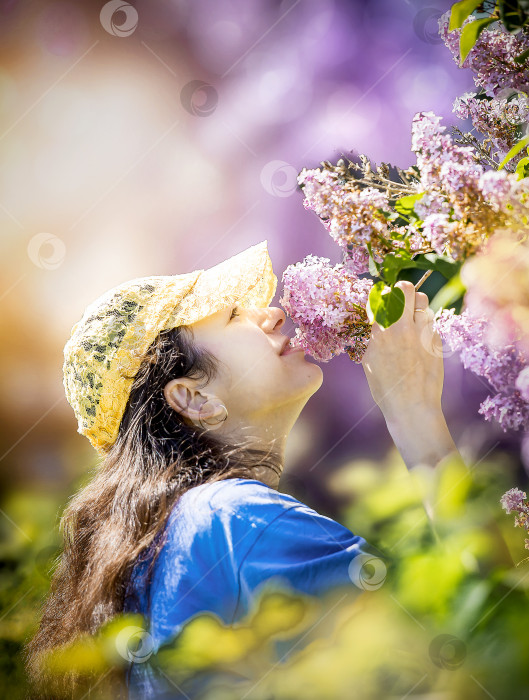 Скачать Девушка вдыхает аромат сирени в саду фотосток Ozero