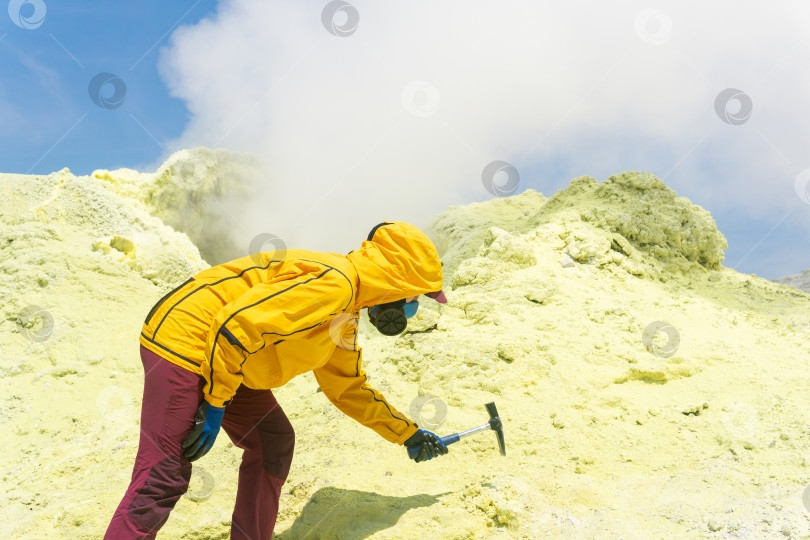 Скачать женщина-вулканолог на склоне вулкана рядом с дымящейся фумаролой берет пробу минерала с края сернистого кратера фотосток Ozero