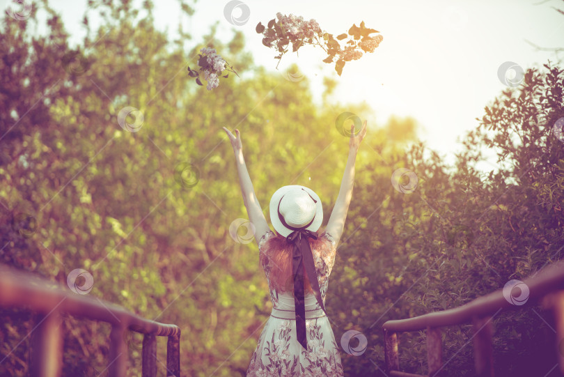 Скачать Девушка в шляпе подбрасывает цветы, стоя спиной к мосту, подтянутая фотосток Ozero