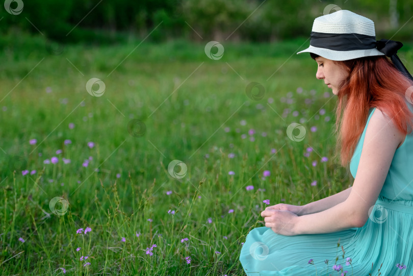 Скачать Девушка в голубом платье сидит на цветочном поле фотосток Ozero