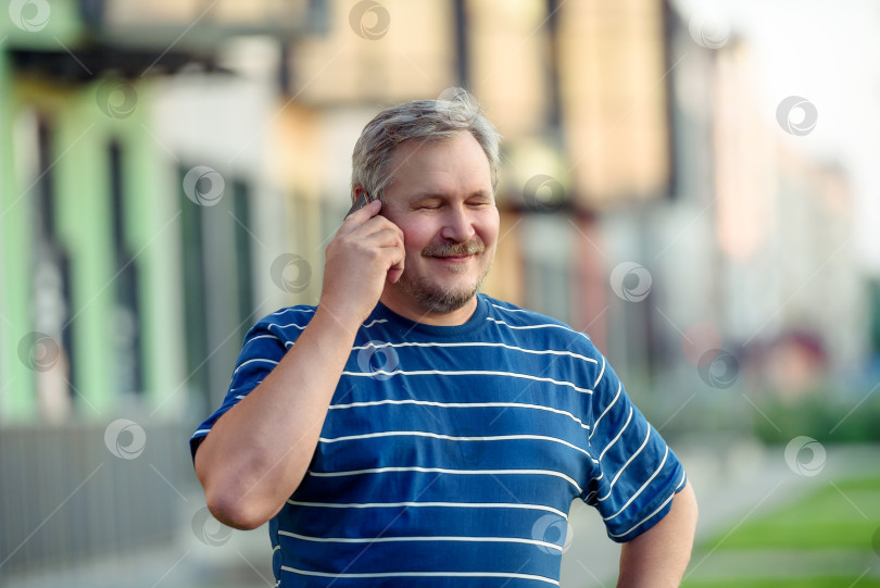 Скачать Мужчина счастливо закрыл глаза, разговаривая по смартфону на улице фотосток Ozero