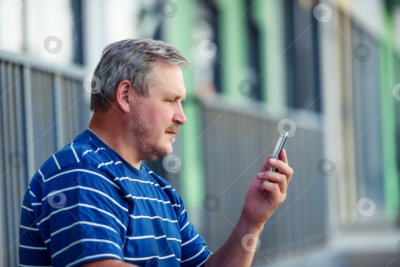 Скачать Красивый мужчина читает сообщение на смартфоне в городе. Портрет крупным планом.m фотосток Ozero