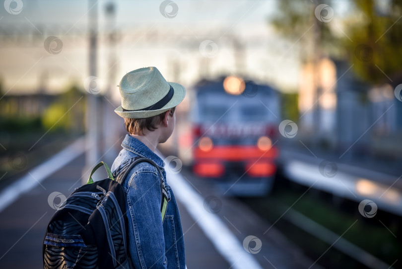 Скачать Парень с рюкзаком путешественника на перроне ждет поезд фотосток Ozero