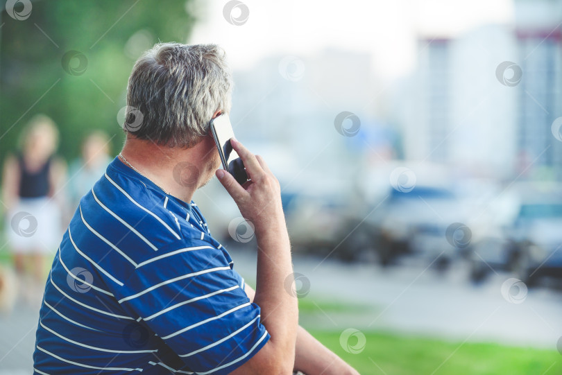 Скачать Мужчина разговаривает по телефону в городе - портрет мужчины, использующего устройство, вид сзади фотосток Ozero