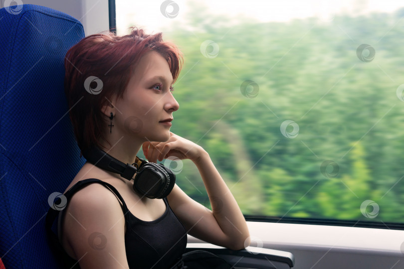 Скачать девушка едет в пригородном поезде и смотрит в окно на природный пейзаж, размытый в движении фотосток Ozero