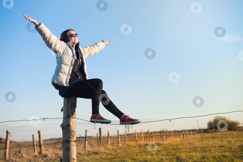 Скачать Молодая девушка идет по полю с поднятыми к небу руками фотосток Ozero
