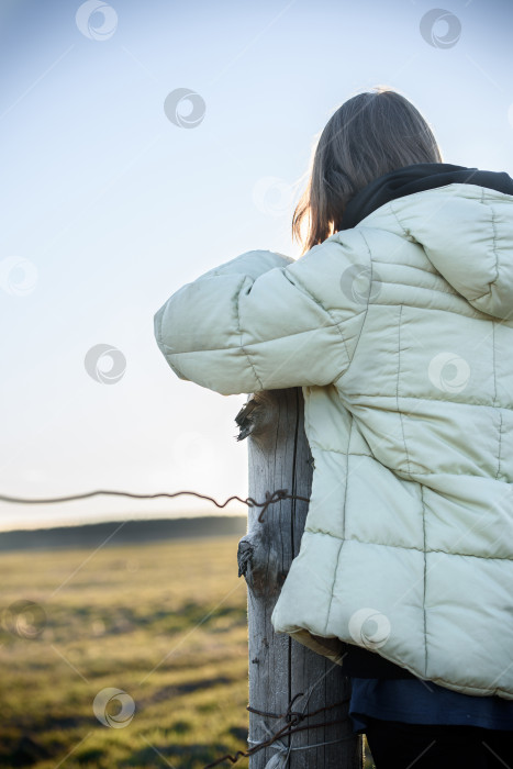 Скачать девочка-подросток стоит за забором в деревне и смотрит в поле фотосток Ozero