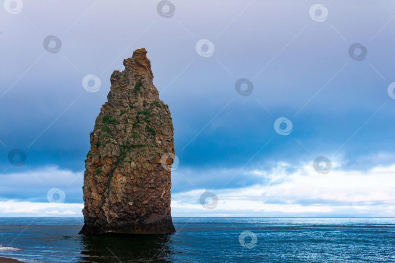 Скачать морской пейзаж Кунашира, океанский берег с огромной вертикальной скалой в воде фотосток Ozero