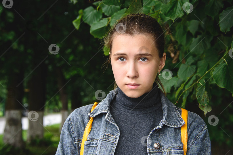 Скачать Портрет грустной девушки в парке на фоне зелени крупным планом. фотосток Ozero