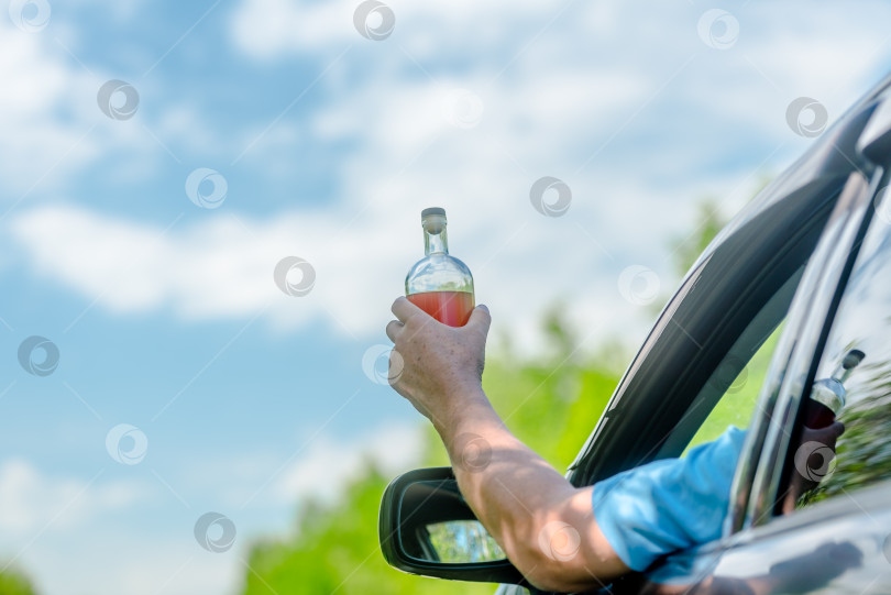 Скачать Человек употребляет алкоголь за рулем - понятие вождения в нетрезвом виде. Закройте руку бутылкой с алкоголем фотосток Ozero