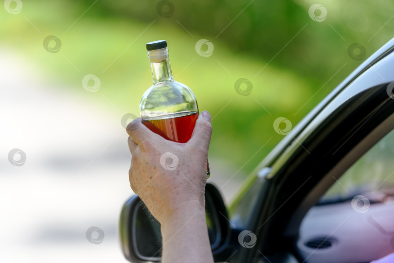 Скачать Человек, который держал в руке бутылку с алкоголем, управляя автомобилем. Понятие вождения в нетрезвом виде фотосток Ozero