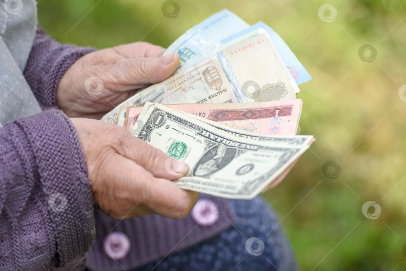 Скачать Пожилая женщина рассматривает банкноты - руки и деньги крупным планом фотосток Ozero