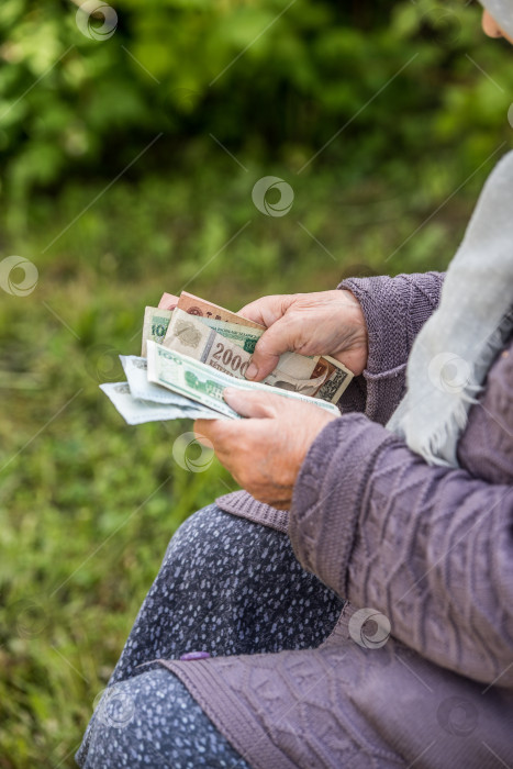 Скачать Пожилая женщина рассматривает банкноты - руки и деньги крупным планом фотосток Ozero