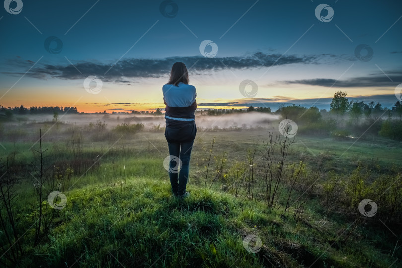 Скачать Девушка стоит на холме и смотрит на закат сквозь туман фотосток Ozero