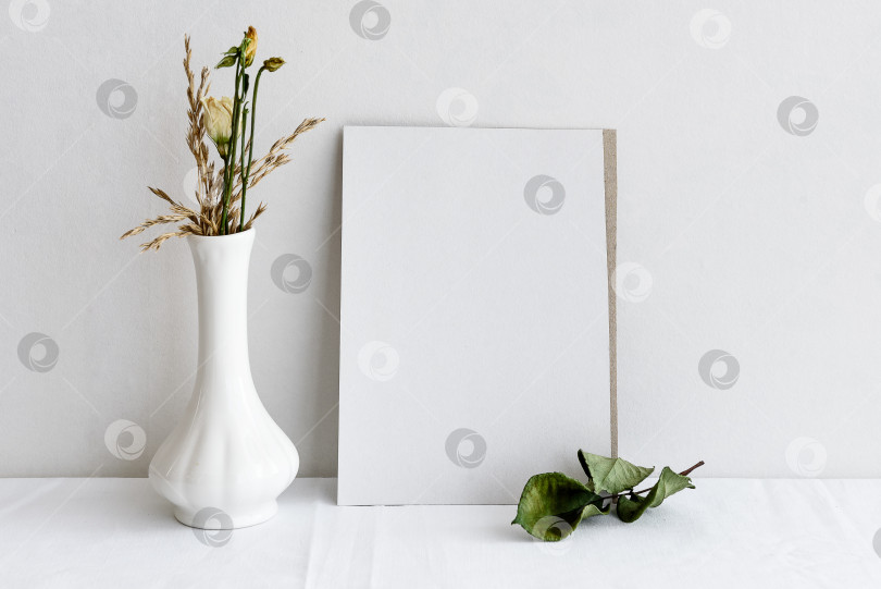 Скачать Пустая белая поздравительная открытка и засушенные цветы в вазе на белом фоне. Романтический фон для приглашения. фотосток Ozero