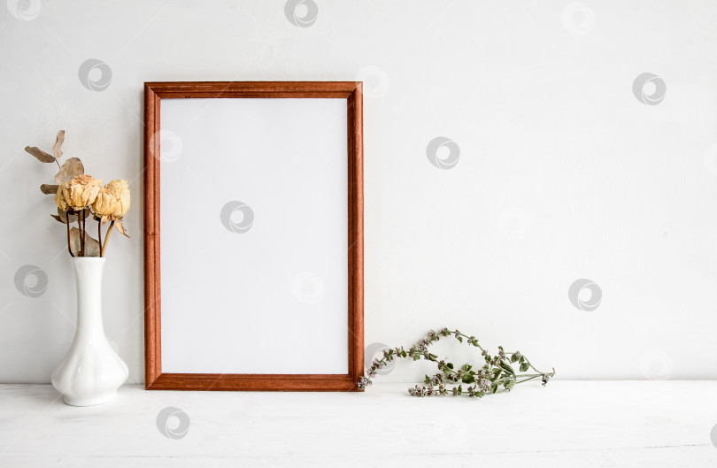 Скачать Пустая деревянная рамка для фотографий на белом столе и цветы в вазе. Модный свадебный или праздничный баннер. фотосток Ozero