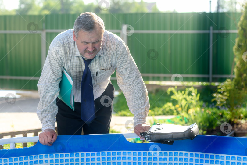 Скачать бизнесмен с папкой под мышкой смотрит на бассейн фотосток Ozero